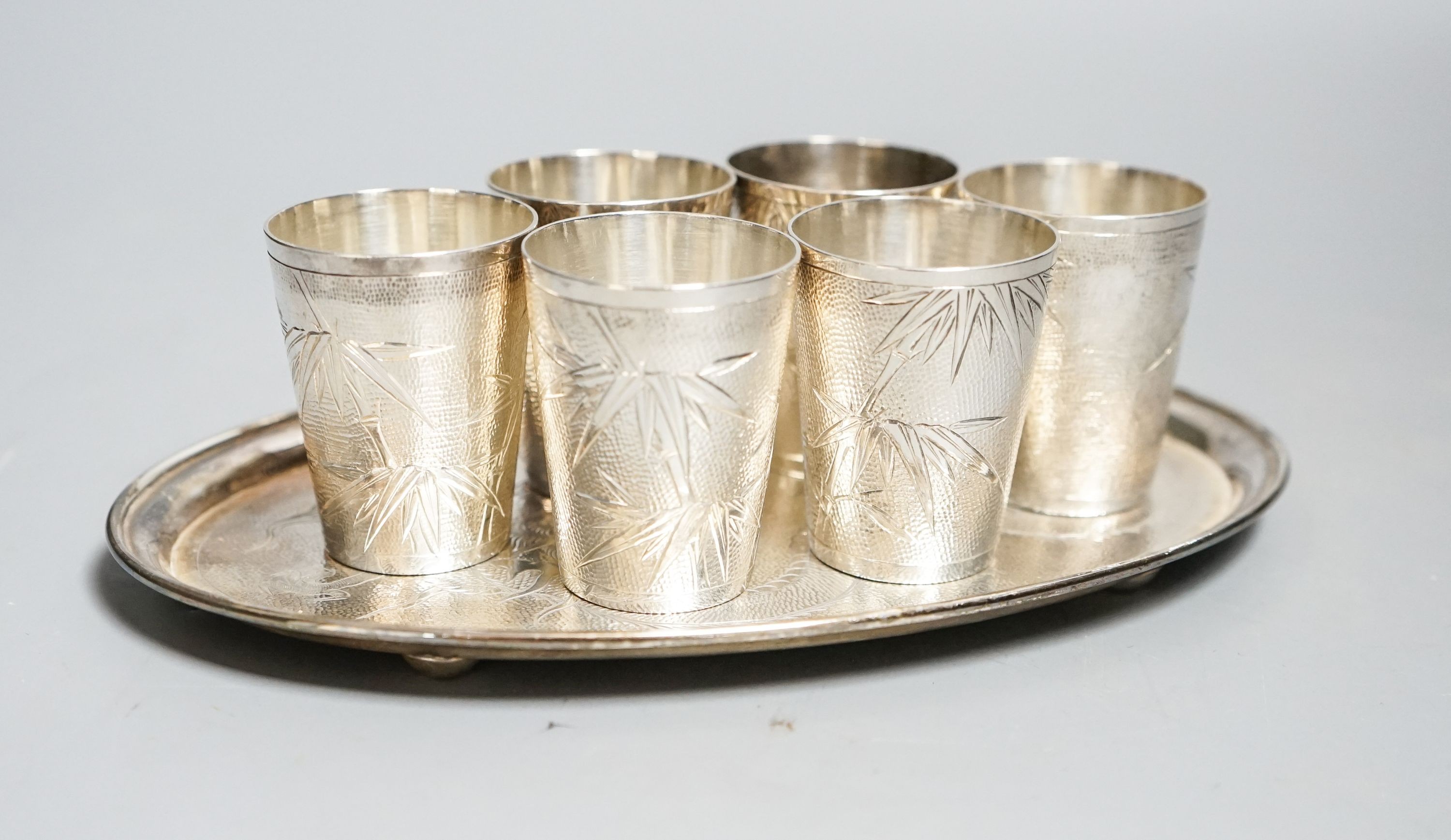 A set of six Chinese white metal tots by Tack Hing, 50mm and a small oval tray by Kingsburg, Hong Kong, 10.5oz.